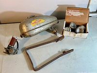 Overview of tank, mounting bracket, fuel pump assembly and box of bearings on table