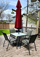 Full setup on wooden deck showing table, chairs, umbrella and base