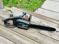 Side angle showing the full length of the Remington electric chainsaw with power cord and 14 inch saw bar and chain.