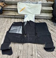 Black floor carpet with vinyl patch laid out on wood deck showing size and texture.