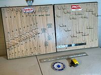 Two Proto wooden tool hanging racks: one for metric wrenches with printed sizes and metal hooks, the other with multiple metal hooks for hammers. Additional items include a metal ruler, a tape measure, and a temperature gauge.
