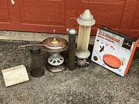 Wide shot showing five assorted bird feeders and boxed All Seasons heated birdbath on pavement against red door
