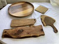 Set of five wooden charcuterie boards displayed on a white sheet, showing size and wood grain details