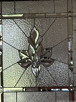 Front view of entire clear stained glass panel showing central motif and textured border