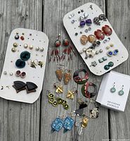 Full spread of pierced earrings on display cards and loose