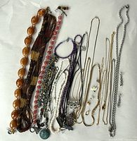 Photo showing full assortment of costume jewellery laid out including necklaces, bracelets, and earrings on white background.
