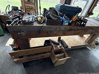 Overall view of wooden bench holding power tools, clamps, bit set, workbench and bags
