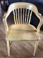 Front view of solid oak bankers chair showing the vertical slat back and curved armrests.