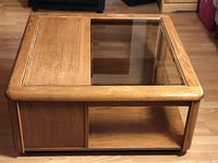 Top angled view of oak coffee table showing partial beveled glass top and wood panel on top surface, cabinet side panel visible.