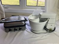 Cuisinart 5-in-1 Griddler and Braun Mixer together on table near window showing overall condition and items included.