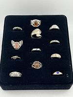 Top view of 12 sterling silver rings displayed in black velvet holder showing variety of stones and designs