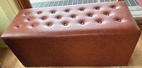 Front view of rectangular faux leather storage bench with button-tufted cushioned top.