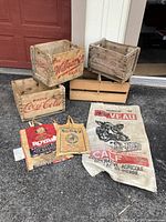 Photo showing two Coca-Cola wooden boxes, one Wilson Ginger Ale wooden box, unmarked wooden box, and three woven bags.