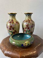 Front view of the two cloisonné vases and bowl showing floral motifs on vases and dragon motif on bowl