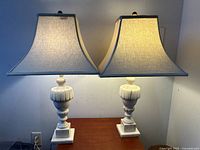 Pair of antique alabaster lamps illuminated on wooden table, showing overall form and shade shape