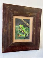Framed oil painting of a frog with visible signature and wooden frame with wear.
