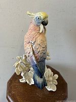 Front and side views of the porcelain cockatoo bird sculpture in pastel colors on a white floral base.