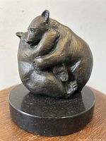 Front view of the bronze sculpture depicting two playful bears embracing on a circular black marble base, highlighting the texture and artistry.