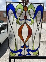 Full view of stained glass panel held up to natural light showing colors and design.