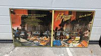 Double-sided framed poster showing front and back of Pat Travers Band's 1978 'Heat In The Street' album cover artwork with autographs.