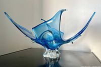 Front angle view of the large blue gradient glass bowl with wave splash design on a dark surface.