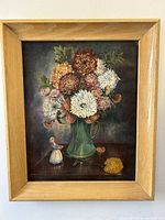 Front view of the framed oil painting showing a bouquet of chrysanthemums in a green vase with a figurine and signed by Joan Dunn.