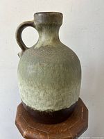 Front view of MCM West German pottery jug vase showing rounded body, short neck, and textured green-brown glaze transitioning from dark brown base to light top.