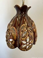Close-up view of the ceramic lamp showing brown glaze with carved floral cutout design.