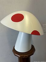 Side view of the white metal mushroom lamp with red spots on the cap, showing the shape and design.