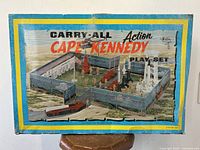 Front of original carrying case showing the Cape Kennedy playset illustration with fencing, figures, and rockets.
