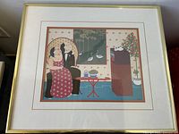 Framed art print showing a surreal image of a couple watching TV with decorative elements in the room.