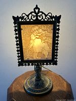 Front lit lithopane showing detailed image of two children and a dog with a floral element, set in ornate metal frame and base