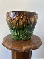 Front view of the vintage McCoy planter showing brown to green glaze and sun/moon grass motif.