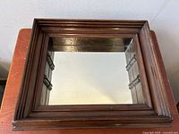 Front view of vintage wood framed shadow box mirror showing carved wooden frame and reflective mirror surface.