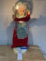 Front view of Mrs. Claus figure lit and raised arm holding candle