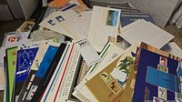 Stacked assortment of stamp folders, presentation sheets and loose covers