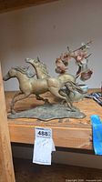 Brass horse sculpture beside faux flower bonsai
