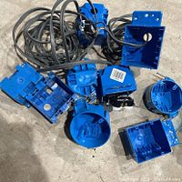 Pile of blue PVC electrical boxes with black cord