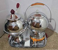Overall view of both urns on tray, one lid removed