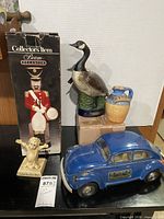 Group shot showing boxed Nutcracker decanter, Canada goose decanter, blue car decanter, stoneware syrup jug, Serrie & Co figurine