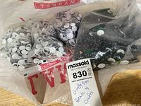 Clear bag holding multiple smaller bags of googly eyes and black beads