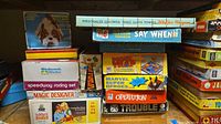 Stacked assortment of ten boxed 1970s board games, rock polisher kit and battery-operated bulldog toy