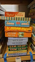 Stack of eight vintage jigsaw puzzle boxes on shelf