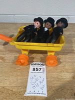 Three tuxedo-clad dolls inside yellow Mattel wagon