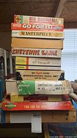 Stack of nine vintage board game and kit boxes showing titles and box wear