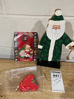 Overview of lot: wooden Santa figure, packaged Looney Tunes ornament, bagged red ornaments