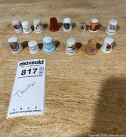 All twelve decorative thimbles displayed in two rows on wooden surface