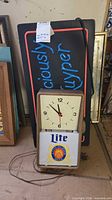 Front view of Miller Lite clock in front of DeKuyper sign, mirror partially visible