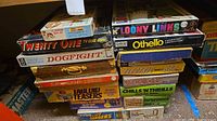 Stacked vintage board games on shelf, various titles visible