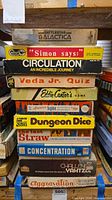 Stack of eleven vintage board game boxes showing titles and wear
